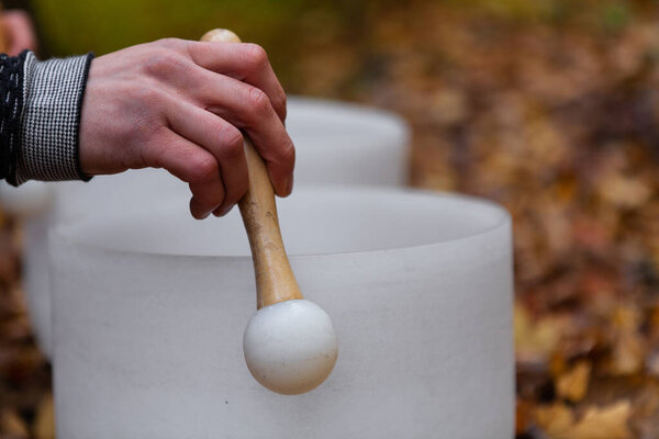 Man plays crystal bowls in the forest in the fall