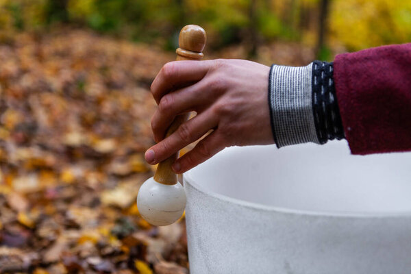 Человек играет в хрустальные чаши в лесу осенью
