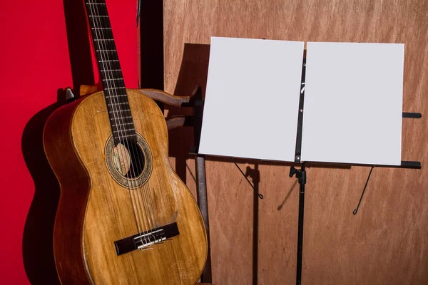 Guitare, chaise et lutrin avec un fond en bois et rouge — Photo