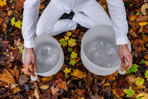 Young man plays his 2 crystal bowls in the forest - pictured from above