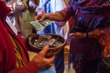 Renkli elbiseli kadın sepete 10 Kanada doları koyuyor.