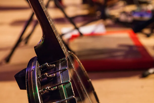Banjo en su stand, retratado en un escenario con pies borrosos tocando el tablero — Foto de Stock
