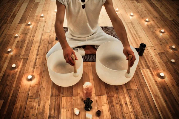 Genç adam meditasyon konseri için kristal kaseler çalıyor.