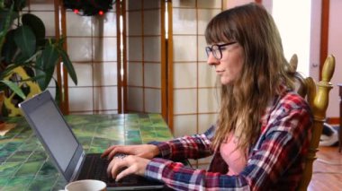 Masadaki kadın dizüstü bilgisayarla çalışıyor.