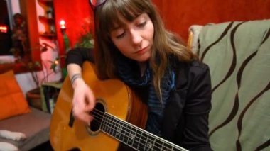 Oturma odasında gitar çalan kız..