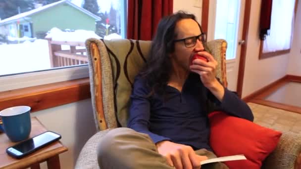 Человек читает книгу в своей гостиной — стоковое видео