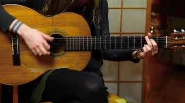 Kız evde klasik gitar çalıyor.
