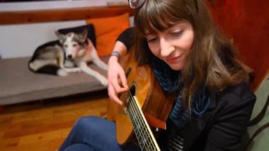 Oturma odasında gitar çalan kız..