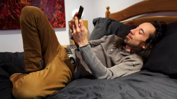 Uomo sul suo cellulare a letto . — Video Stock