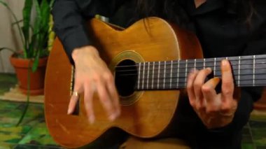 Adam evde klasik gitar çalıyor.