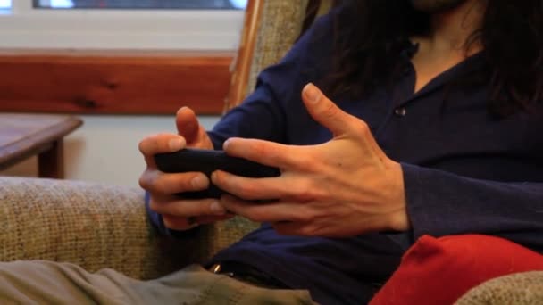 Человек, использующий мобильный телефон в гостиной — стоковое видео