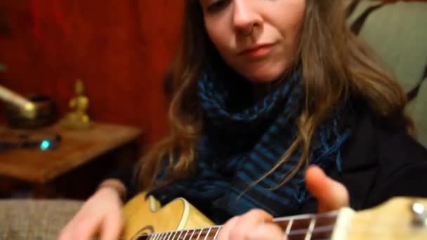 Дівчина грає укулеле у вітальні . — стокове відео