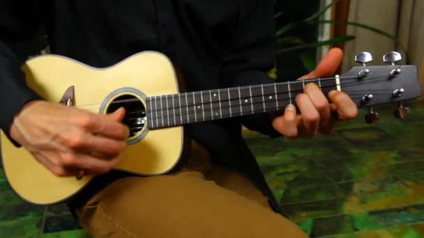 Jovem está jogando em um pequeno ukulele — Vídeo de Stock