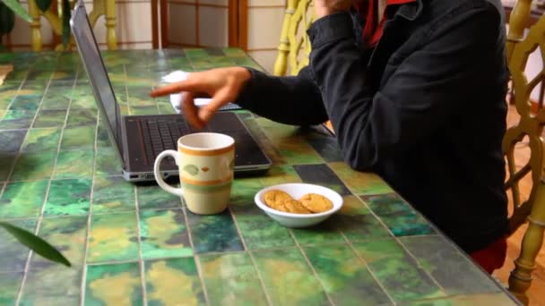 Чоловік за столом працює з ноутбуком — стокове відео