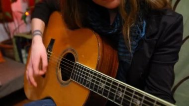 Oturma odasında gitar çalan kız..
