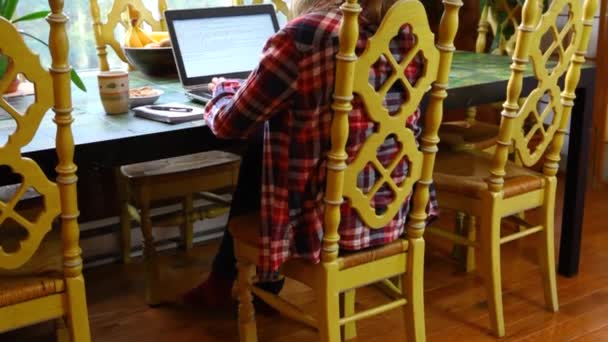 Vrouw aan tafel werkend met laptop — Stockvideo