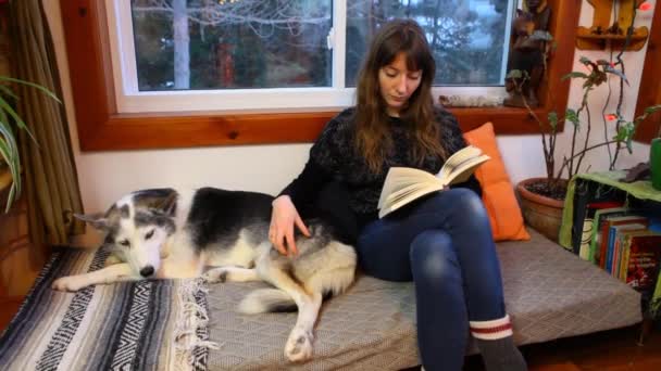 Meisje leest een boek in een woonkamer — Stockvideo