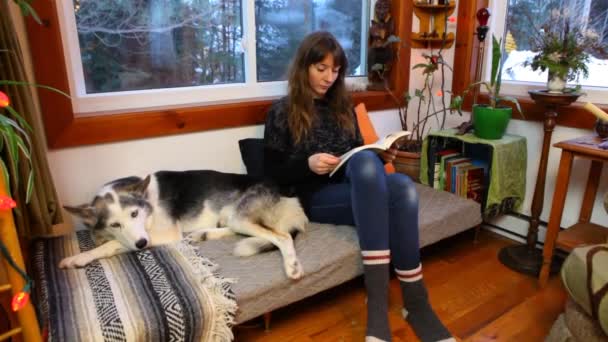 Meisje leest een boek in een woonkamer — Stockvideo