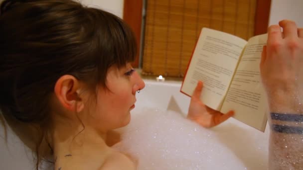 Girl reading a book in the bathtub. — Stock Video