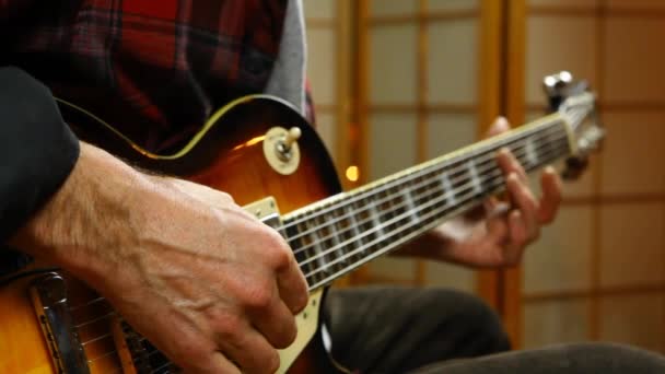 Az ember harmonikával hangolja a gitárját. — Stock videók