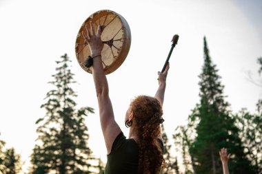 woman holding sacred drum in the sky clipart