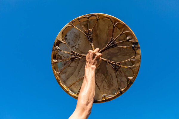 man holding sacred drum up in the sky