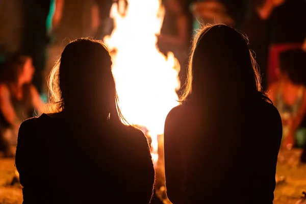 Ateşin önünde oturan iki kız.