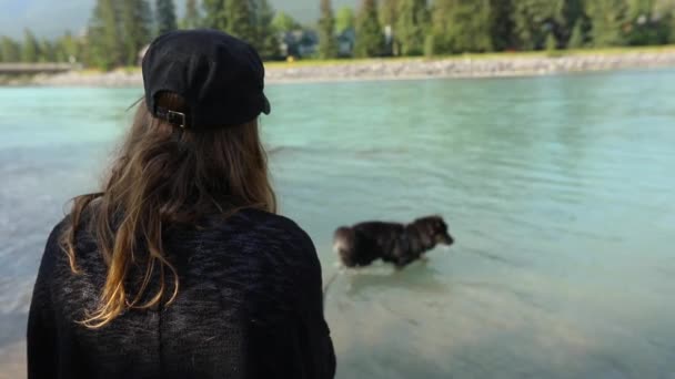 Kobieta pilnuje psa w górskim jeziorze — Wideo stockowe