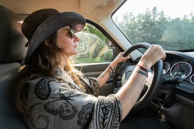 Beyaz bir kadın ormanda SUV kullanıyor.