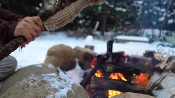 Native man stokes camp fire in winter — Stock Video