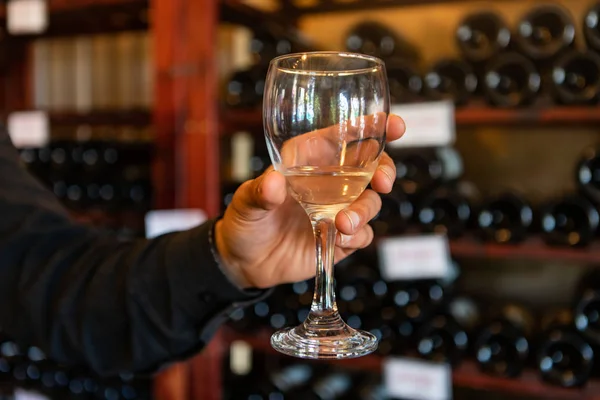 Una copa de vino blanco en la mano del hombre — Foto de Stock