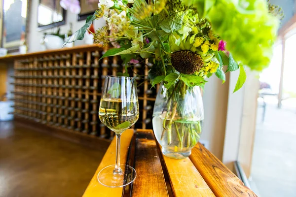 Glas vitt vin och blommor vas — Stockfoto