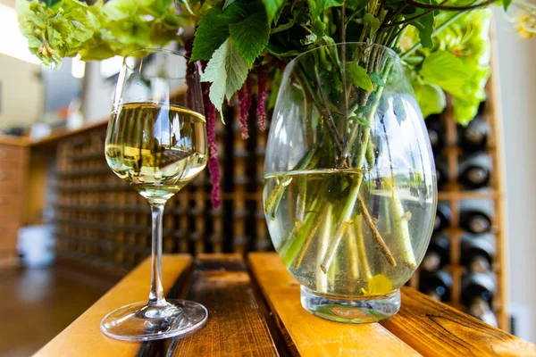 Glass of white wine and flowers vase — 스톡 사진