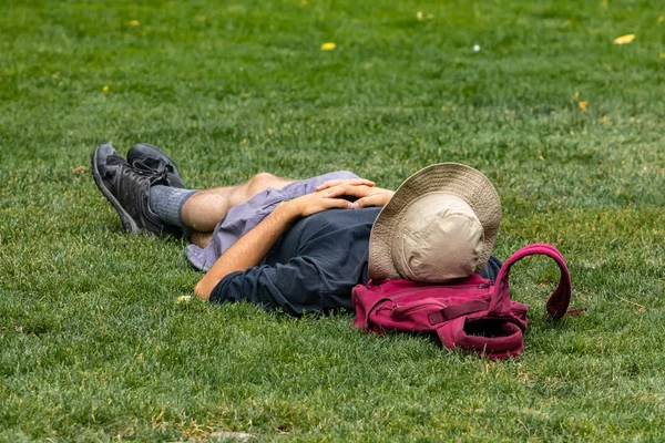 Muž se slunečním kloboukem zatímco ležel na trávě — Stock fotografie