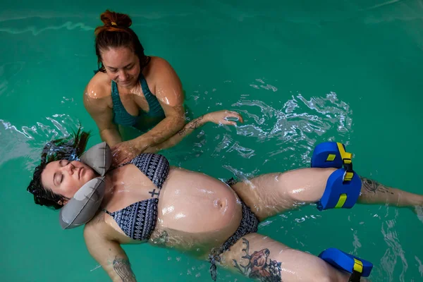Nő segít terhes hölgy lebegni a vízen — Stock Fotó
