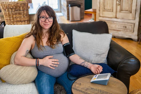 Беременная женщина использует измеритель артериального давления — стоковое фото