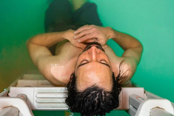 Jovem descansando na piscina apoiando-se na escada — Fotografia de Stock