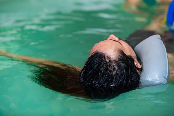 Молодий чоловік з довгим волоссям плаває на воді — стокове фото