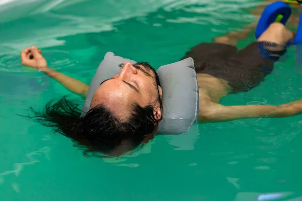 Joven flotando en el agua en la piscina —  Fotos de Stock