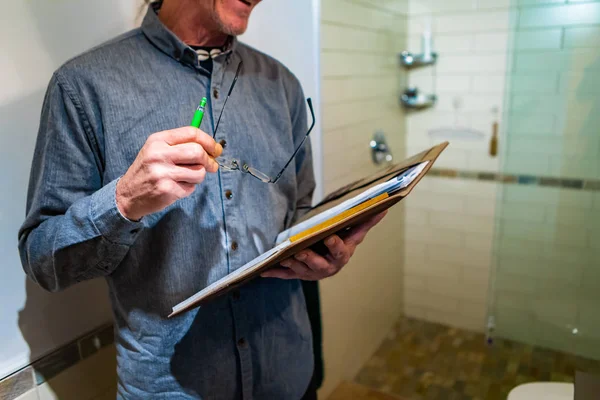 Hombre sosteniendo un cuaderno, bolígrafo y gafas — Foto de Stock