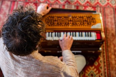 Man playing soulful music with harmonium clipart