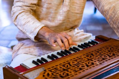 Male hands playing keys on harmonium 