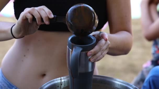 Женщина наливает шоколад в бутылку и чашку — стоковое видео