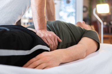Spor fizyoterapisti güçlü bir adama masaj yapıyor.