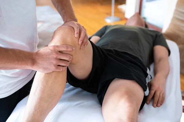 Spor fizyoterapisti güçlü bir adama masaj yapıyor.