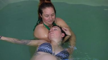 Aqua eğitmeni hamile kadına masaj yapıyor.