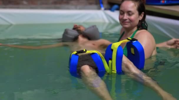 Genç adam havuzda su bacağı masajı yaptırıyor. — Stok video