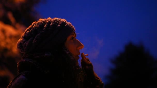 Meisje buiten roken in de winter, 's nachts in de winter — Stockvideo