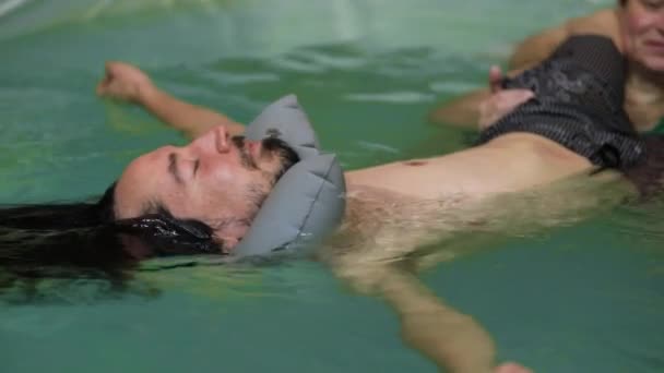 Entrenador dando spa de cuerpo completo para el hombre en la piscina — Vídeo de stock