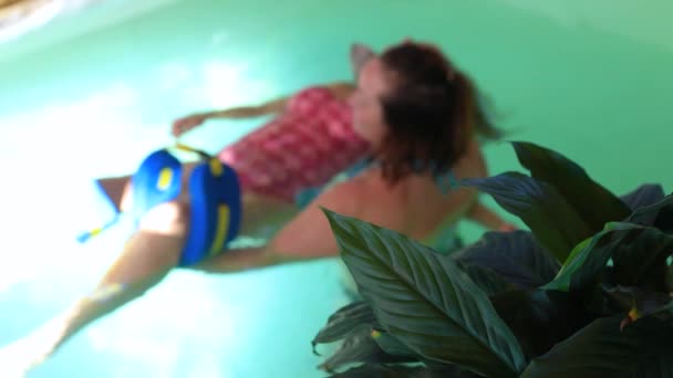 Старшая женщина отдыхает в бассейне с терапевтом — стоковое видео